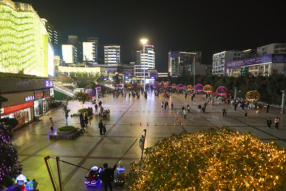 夜晚城市广场，灯火璀璨，人流如织